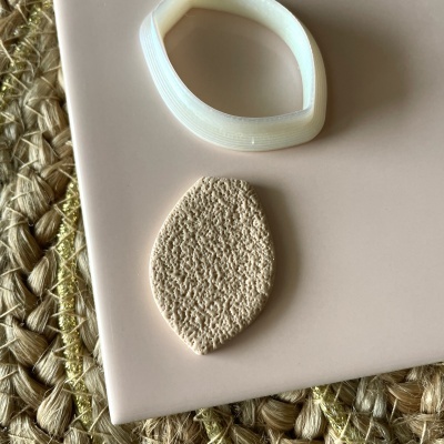 Duas peças de joia em superfície rosa claro sobre tapete de palha