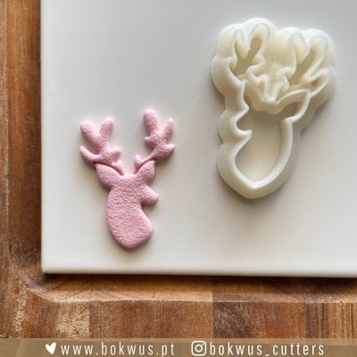 cortador de massa branco em forma de cabeça de rena e peça rosa cortada
