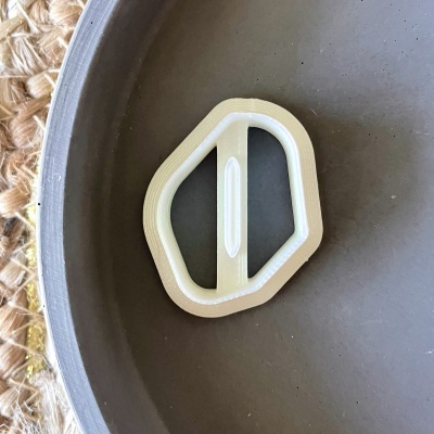 Rebite branco hexagonal com barra central numa tigela cinza sobre tapete de fibras naturais