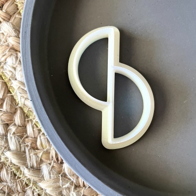 Utensílio de cozinha branco em forma de meia-lua numa panela preta