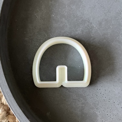 Objeto plástico branco em forma de arco sobre superfície escura circular