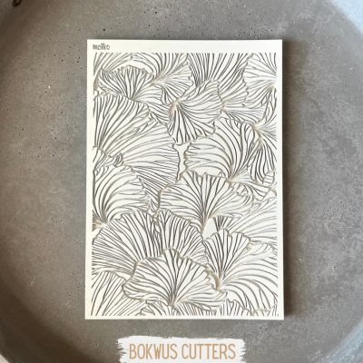 Cartão com desenho de folhas em relevo branco, linhas pretas e douradas