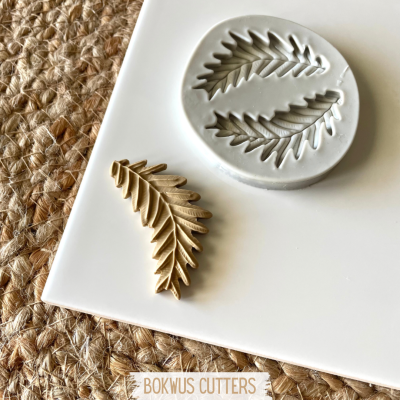 Molde de silicone cinzento e peça moldada bege em placa branca sobre tecido trançado