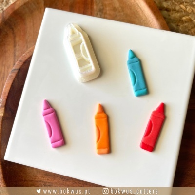 Cinco gizes coloridos em forma de lápis de cera sobre prato quadrado branco