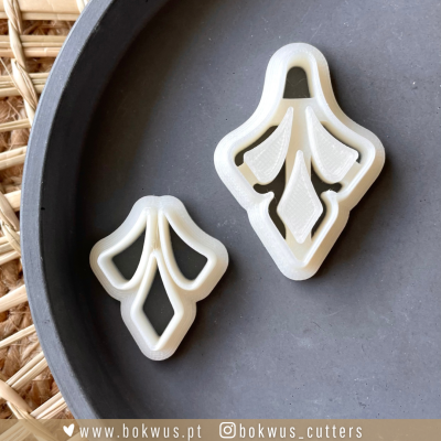 Dois cortadores de biscoito brancos com padrão geométrico em tabuleiro cinzento