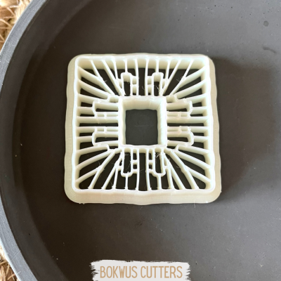 Cortante quadrado branco em superfície escura com etiqueta BOKWUS CUTTERS