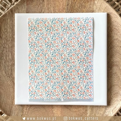 Papel de embrulho floral em placa branca sobre superfície de madeira