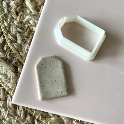 Peças geométricas branca e bege sobre superfície rosa e tecido trançado