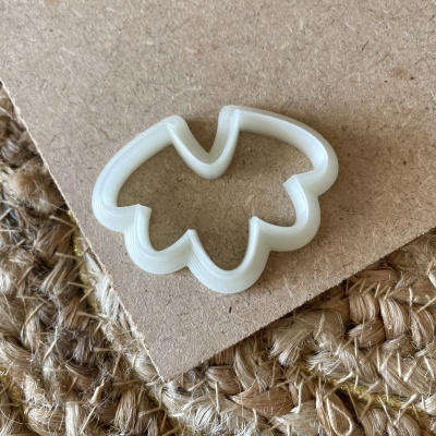 Cortador de bolachas branco em formato de folha sobre cartão e tecido