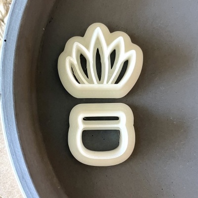 Dois cortadores de biscoitos brancos em forma de planta sobre superfície cinza