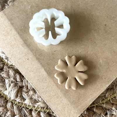 Cortador de biscoitos em plástico branco com massa moldada em forma de flor e fundo de cartão e fibra natural