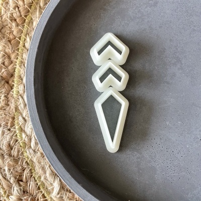 Cortadores de biscoito brancos em formas geométricas numa prato cinzento