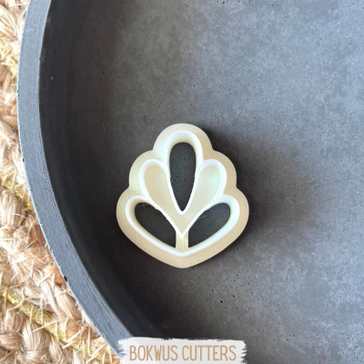 Cortador de bolachas em forma de flor branca sobre prato escuro e base de palha