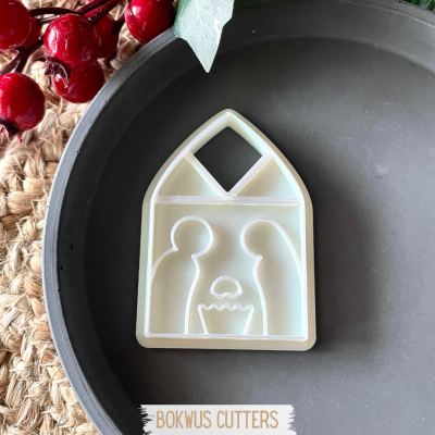 Cortador de biscoitos branco em forma de presépio sobre prato preto