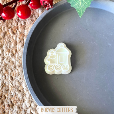 Cortador de biscoitos em forma de comboio creme numa base cinza com decoração festiva