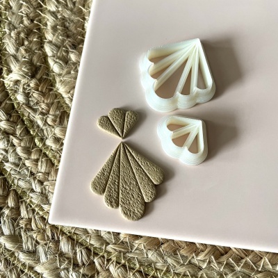 Conjunto de cortantes de leque em plástico branco com forma em couro bege recortada, sobre base rosa e tapete trançado