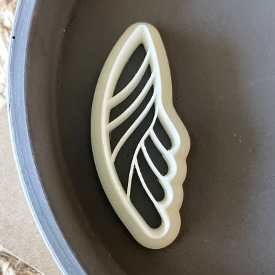 Objeto branco em forma de asa dentro de tigela cinzenta