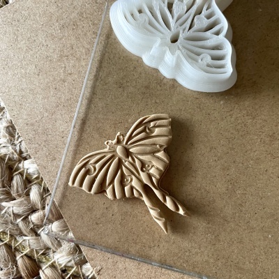 Borboleta decorativa de madeira clara com forma branca em plástico para moldar sobre base de madeira