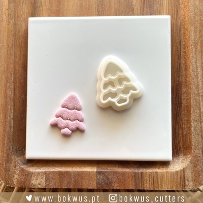 Cortador de biscoitos árvore de Natal e biscoito decorado em prato branco sobre madeira