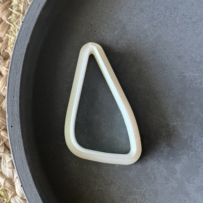 Objeto triangular de plástico creme em prato preto sobre fundo tecido