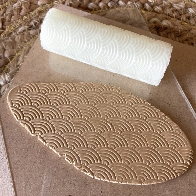 Rolo texturizador branco com padrão de ondas e massa bege com o padrão impresso