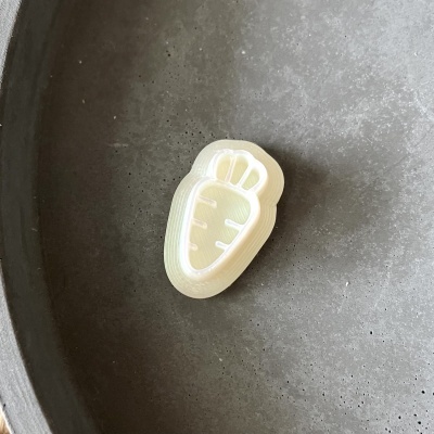 Botão em forma de cenoura transparente com relevo numa superfície cinzenta