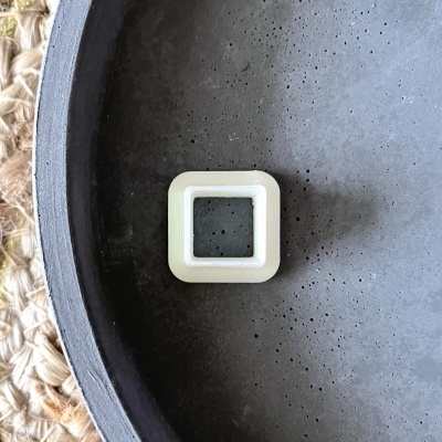 Peça quadrada branca de plástico dentro de recipiente cinza texturizado