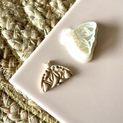 Moldes para bijuteria em formato de asas de borboleta sobre mesa rosa e tapete de fibras naturais