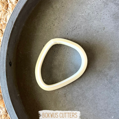 Cortador triangular branco numa superfície cinza com etiqueta BOKWUS CUTTERS