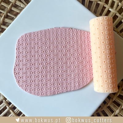 Rolo de textura e placa de pasta cor de rosa com padrão de corações