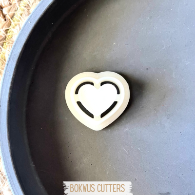 Cortador de biscoitos em forma de coração branco numa bandeja preta