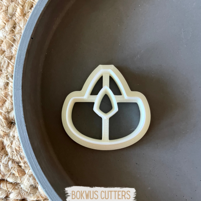 Forma para cortar massa em forma de vela de chá numa tigela cinza