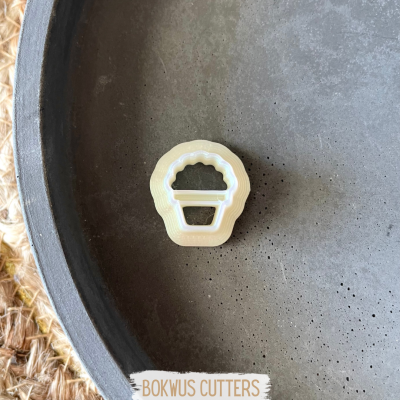 Cortador de massa forma cupcake bege numa superfície cinza