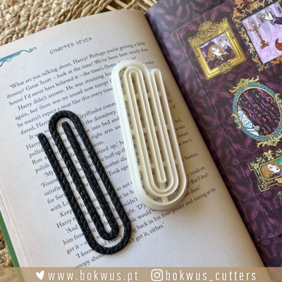 Livro aberto com dois marcadores de livro preto e branco em formato de clipe