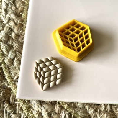 Dois objetos hexagonais geométricos amarelo e branco sobre superfície branca e tapete trançado