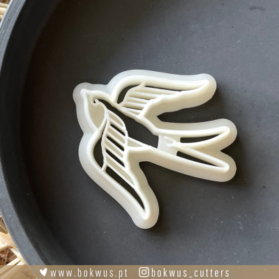 Cortador de biscoitos em forma de pássaro branco sobre prato preto