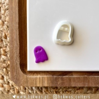 Cortante de fantasma branco e pequeno fantasma roxo sobre superfície branca e madeira