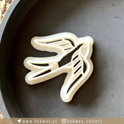 Cortador de biscoitos em forma de pássaro branco sobre fundo escuro