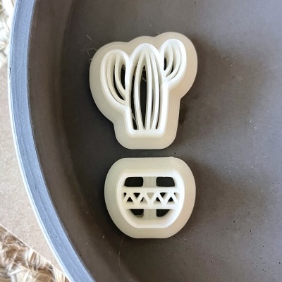 duas formas de plástico branco, uma com formato de cacto e outra quadrada com padrão geométrico