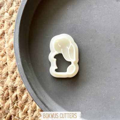 Cortador de biscoitos branco em forma de coelho numa travessa preta redonda