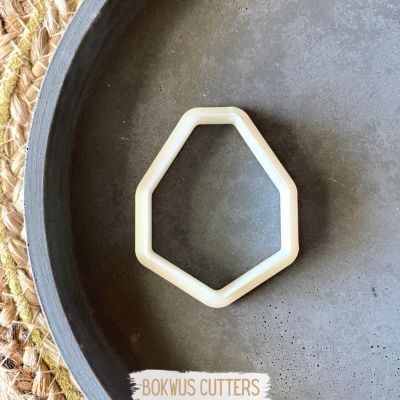 Cortador hexagonal branco sobre prato cinza com tapete de fibras naturais