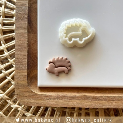 Cortante de porco-espinho branco e figura castanha em base branca sobre bandeja de madeira