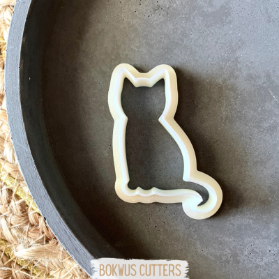 Molde para bolachas em formato de gato em prato cinza escuro perto de base têxtil