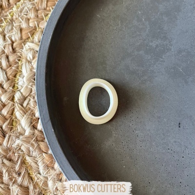 Anel branco numa bandeja preta sobre superfície trançada