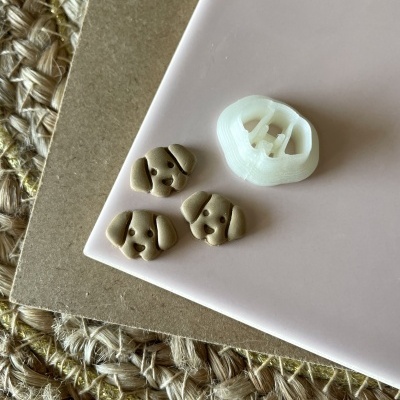 Botões em forma de cabeça de cão com cortador branco sobre papel rosa e tapete texturado