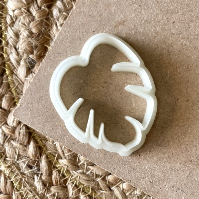 Cortador de bolachas branco em cima de cartão castanho e tecido de ráfia