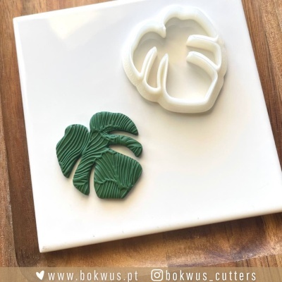 Molde cortador branco e peça verde com textura de folha tropical