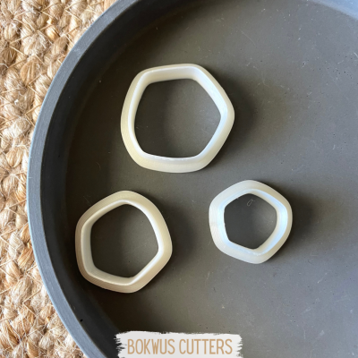 Três cortadores de massa brancos em formato irregular sobre prato cinza escuro