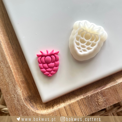 Cortador de biscoitos em forma de framboesa com massa rosa cortada