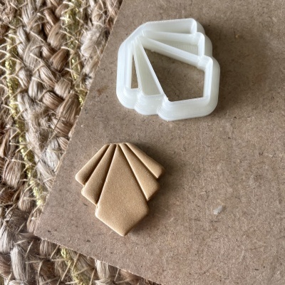 Clipes em forma de losango em plástico branco e cartão castanho sobre superfície de madeira com tecido rústico próximo